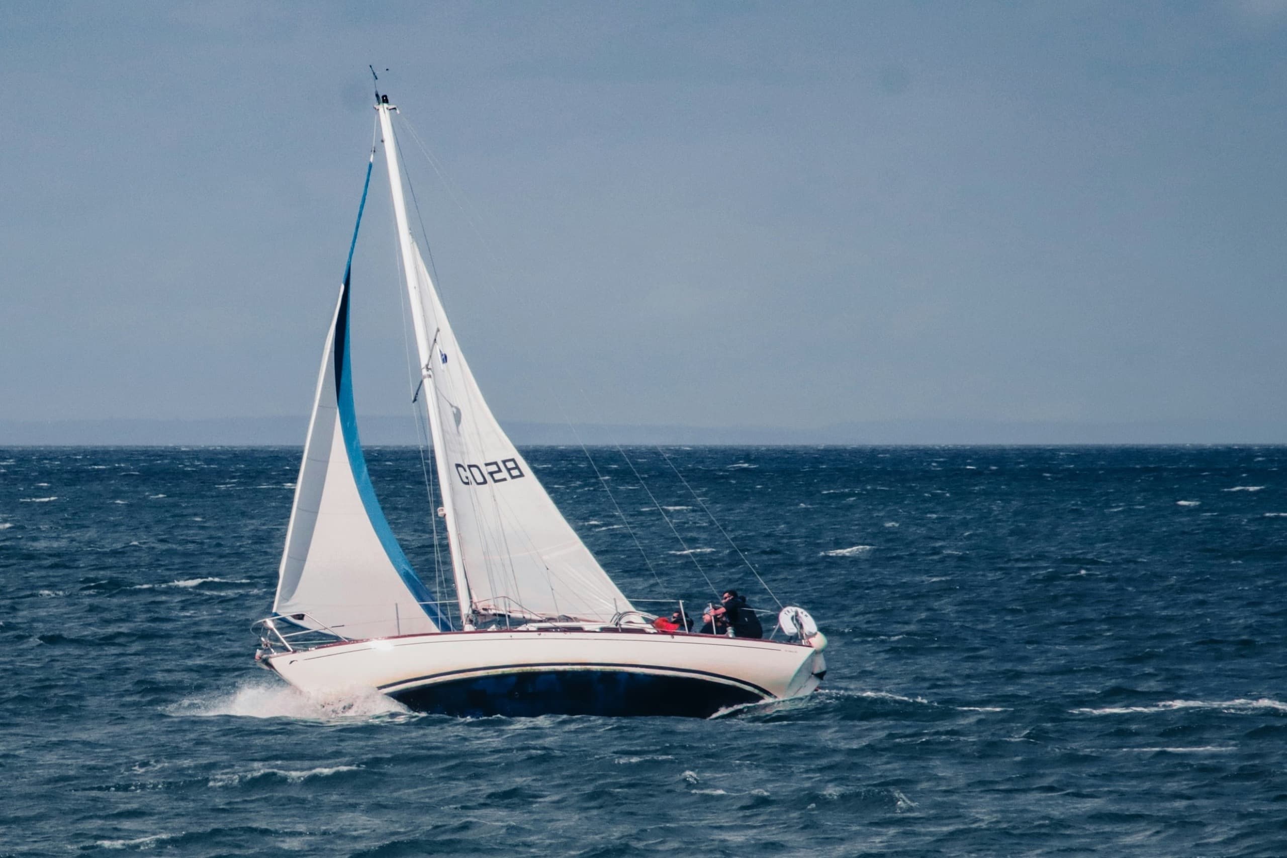 White-sailed keelboat racing across open water